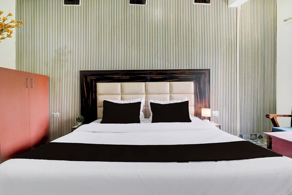 Une chambre d’hôtel avec un grand lit, une tête de lit en bois et un mur à rayures.
