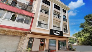 Un hotel de varios pisos con balcones, una fachada comercial y un cielo azul despejado.