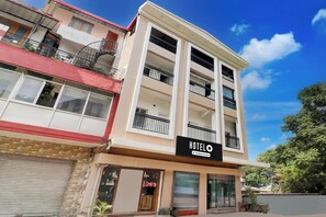 Un hotel de varios pisos con balcones, una fachada comercial y un cielo azul despejado.
