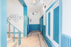 Un pasillo con paredes azules y una escalera de mármol.