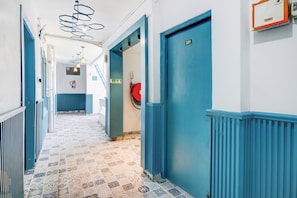 A hallway with blue doors, a fire extinguisher, and a fire hose on the wall.