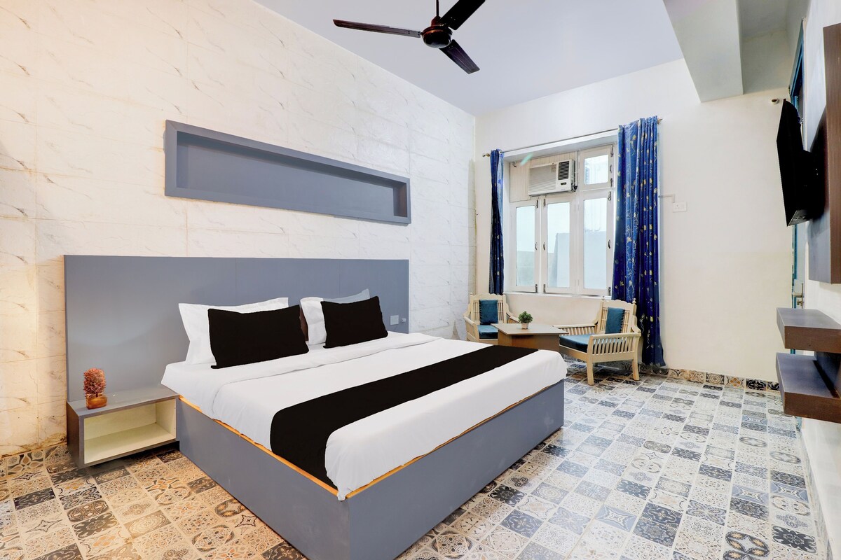 Un dormitorio con cama, escritorio, silla, ventilador de techo y ventana con cortinas.