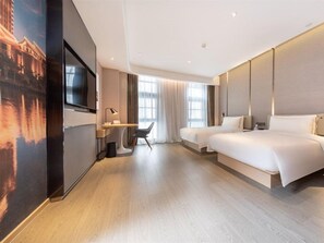 Una habitación de hotel moderna con una cama grande, un escritorio, un televisor y un ventanal amplio.