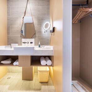 A modern bathroom with a double sink, a mirror with a light, a towel rack, and a wicker basket. - Beijing Road Atour Hotel (Linyi)