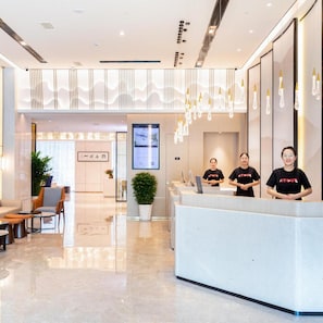 A modern hotel reception area with a glass partition, reception desk, and seating area. - Beijing Road Atour Hotel (Linyi)