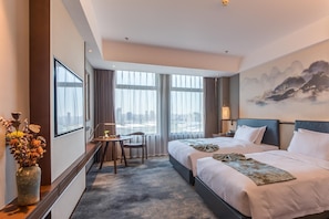 Habitación de hotel con dos camas, un escritorio y vistas a la ciudad.