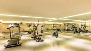 A gym with various exercise machines, a mirrored wall, and a clean, modern design. - Rezen Dong Hotel (Changchun)