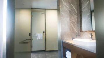 Un baño moderno con cabina de ducha de vidrio, encimera de mármol y un espejo grande.