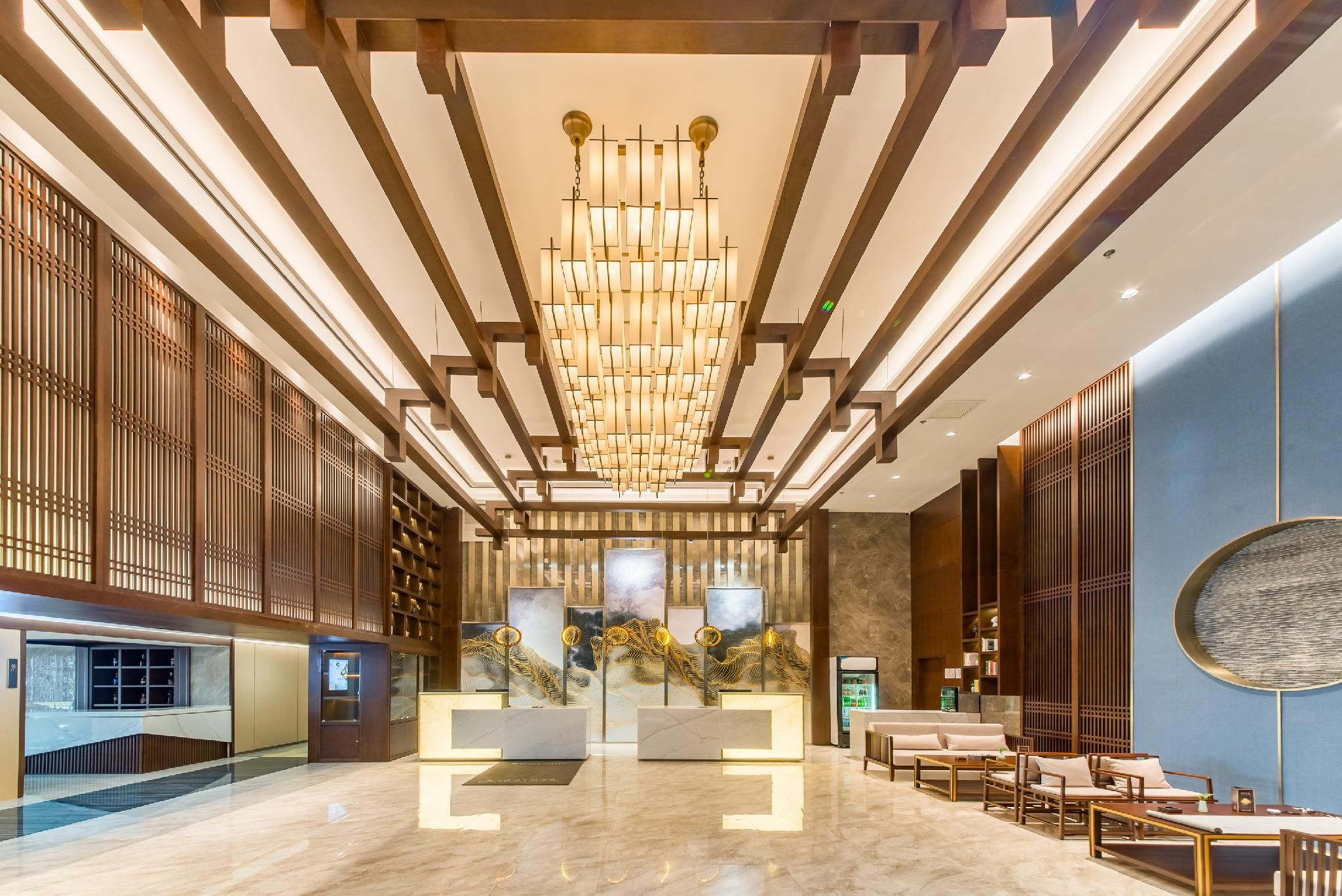 Un vestíbulo moderno con una recepción central, zona de estar y un candelabro decorativo.