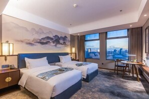 A hotel room with two beds, a desk, a chair, and a large window offering a city view. - Rezen Dong Hotel (Changchun)