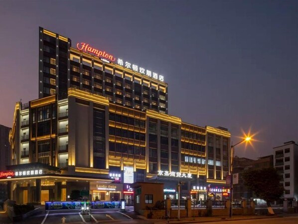 A multi-story hotel with a prominent 'Hampton' sign, multiple balconies, and a well-lit facade. - Hampton by Hilton (Guangzhou)