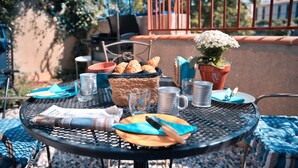 A round metal table with a basket of croissants, a potted plant, and a newspaper. - Vrbo Property (Limoux)