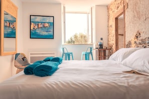 Une chambre d’hôtel avec un lit, une chaise, une table avec une machine à café et deux tableaux au mur.