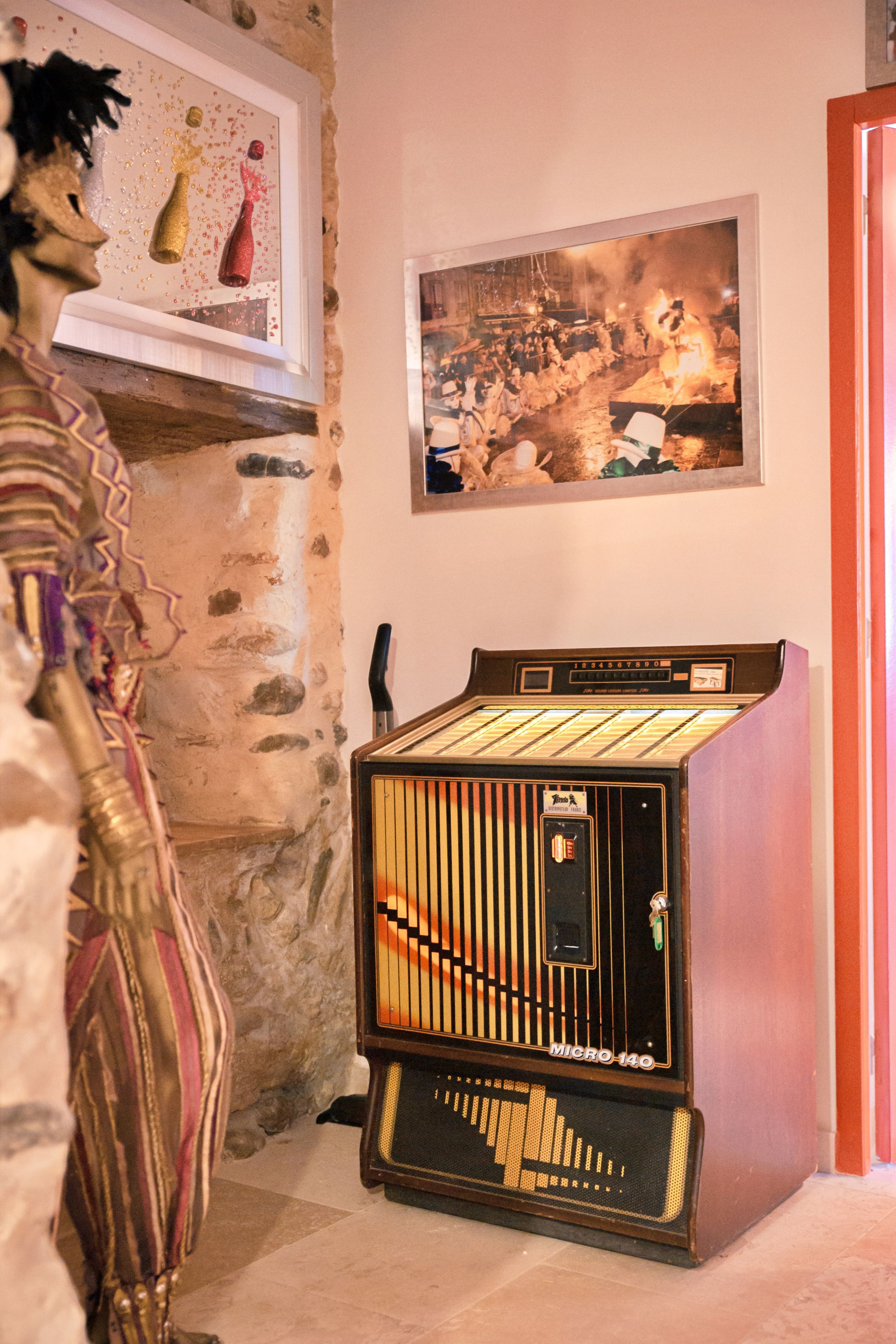 A vintage jukebox, a framed picture, and a statue in a room with stone walls.