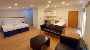 Habitación de hotel con cama, sofá, una mesita, kitchenette y baño.