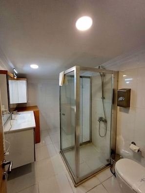 A bathroom with a glass-enclosed shower, a sink, and a toilet. - Del Puerto Hotel Aliaga (Aliaga)