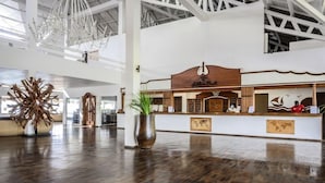 Eine großzügige Lobby mit einem Holzbüro, einer großen Zimmerpflanze und einem modernen Kronleuchter.