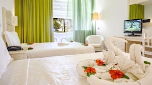 Ein Hotelzimmer mit zwei Betten, einem Schreibtisch mit Computer, einem Sessel und einem Fernseher.