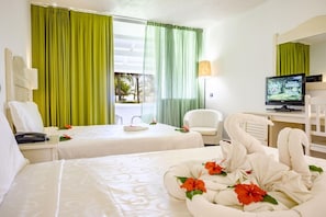 Una habitación de hotel con dos camas, un escritorio con una computadora, una silla y un televisor.