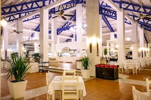 Un amplio comedor interior con techos altos, pilares blancos y numerosas mesas.