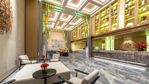 En hotellobby med receptionsdisk, siddeområde og en dekorativ væg.