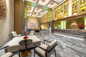 Un hall d’hôtel comprenant un comptoir d’accueil, un espace salon et un mur décoratif.