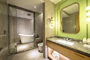 Une salle de bain moderne dotée d’une douche à parois de verre, d’une baignoire sur pieds, d’un meuble-lavabo et d’un grand miroir avec éclairage intégré.