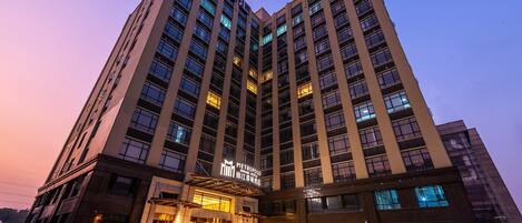A high-rise hotel with multiple floors, a prominent entrance, and a well-lit facade.