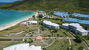 Un resort con alojamiento frente a la playa, una plaza circular central y exuberante vegetación.