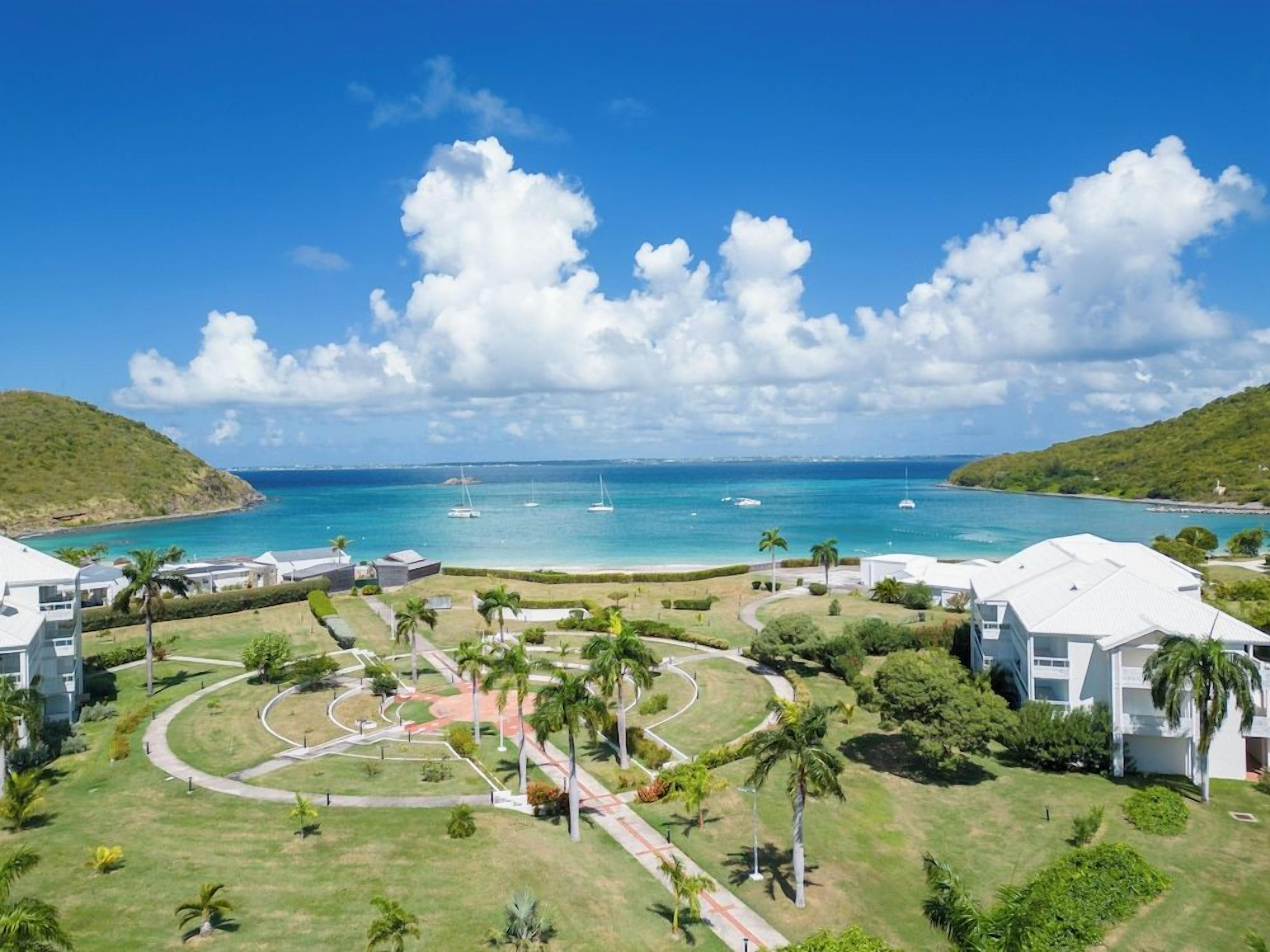 A coastal resort with a clear view of the ocean, a landscaped garden, and modern buildings.