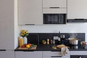 Una cocina con microondas, una olla en la estufa y diversos alimentos sobre la encimera.
