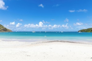 A beach with clear turquoise water, boats, and a distant shoreline. - Anse Marcel Beach Resort (Anse Marcel)