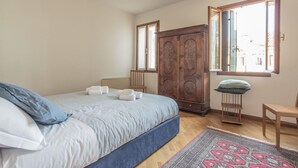 A bedroom with a bed, a wardrobe, a window, and a chair. - Venezia - Castello 1542 (Venice)