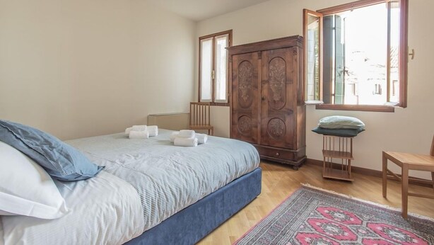 Ein Schlafzimmer mit einem Bett, einem Kleiderschrank, einem Fenster und einem Sessel.