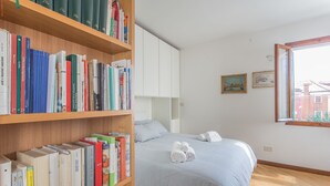 Ein Schlafzimmer mit einem Bett, einem Bücherregal und einem Fenster.