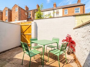 A patio with a table and chairs, a wooden gate, and a white wall. - 9 North Street (Chester)