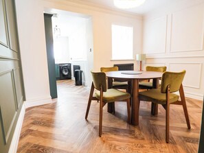 A dining area with a round table and six chairs, a radiator, and a window. - 9 North Street (Chester)