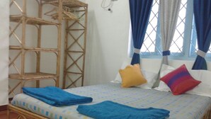 Een kamer met een bed, een rieten stoel en een raam met gordijnen.