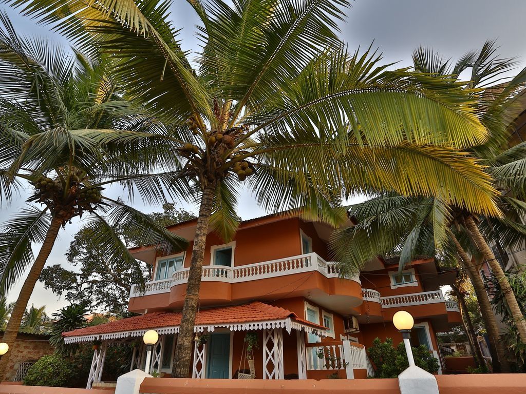A multi-story building with balconies, surrounded by palm trees.