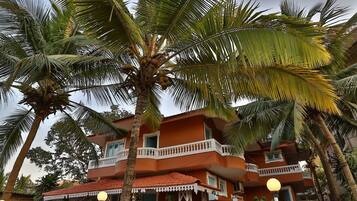 A multi-story building with balconies, surrounded by palm trees.