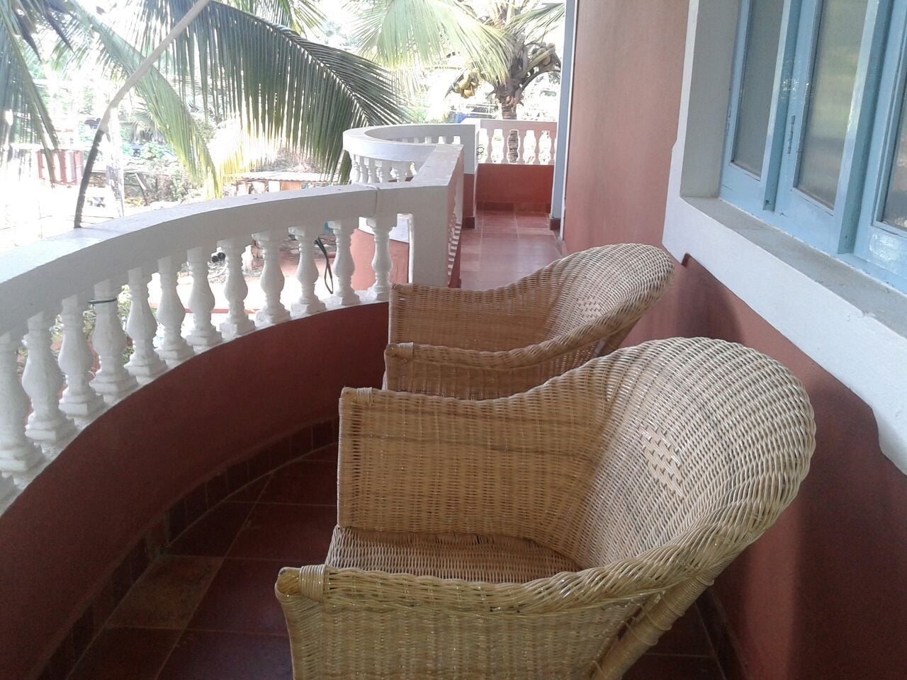 A balcony with wicker chairs and a white balustrade.
