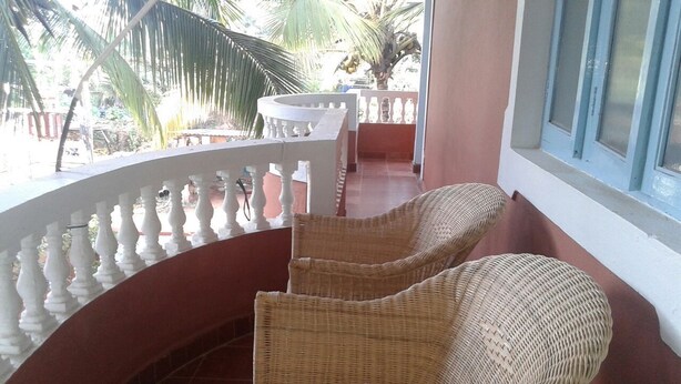 Een balkon met rieten stoelen en een witte balustrade.