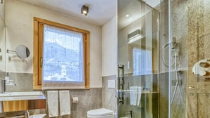 Ein modernes Badezimmer mit Duschkabine aus Glas, Waschbecken und Toilette.