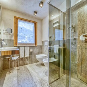 Un baño moderno con cabina de ducha de vidrio, lavamanos y retrete.