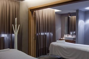 Una habitación de hotel con una cama, un baño con lavamanos y espejo, y una puerta de madera.