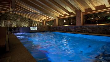 Une piscine intérieure avec des murs en pierre et des poutres en bois.