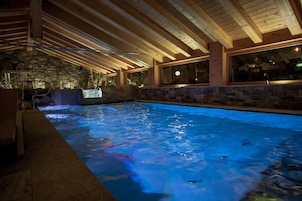 Una piscina interior con paredes de piedra y vigas de madera.