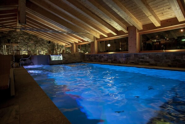Una piscina interior con paredes de piedra y vigas de madera.