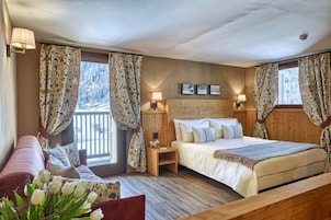 Un dormitorio acogedor con cabecera de madera, cama con ropa de cama blanca, mesita de noche y ventana con cortinas.