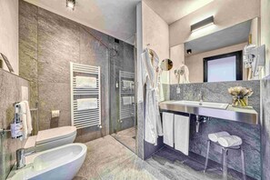 A modern bathroom with a freestanding bathtub, a large mirror, a vanity with a sink, and a shower area.